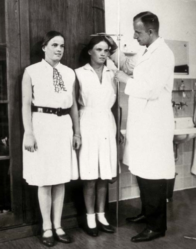 Photograph of Otmar von Verschuer measuring two twins as part of his research into heredity and eugenics. Date is circa 1920s-1940s.